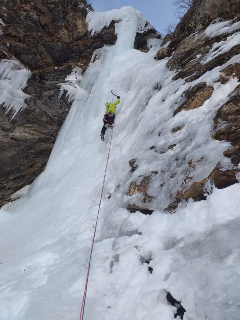 Arrampicatore su cascata di ghiaccio con due picozze